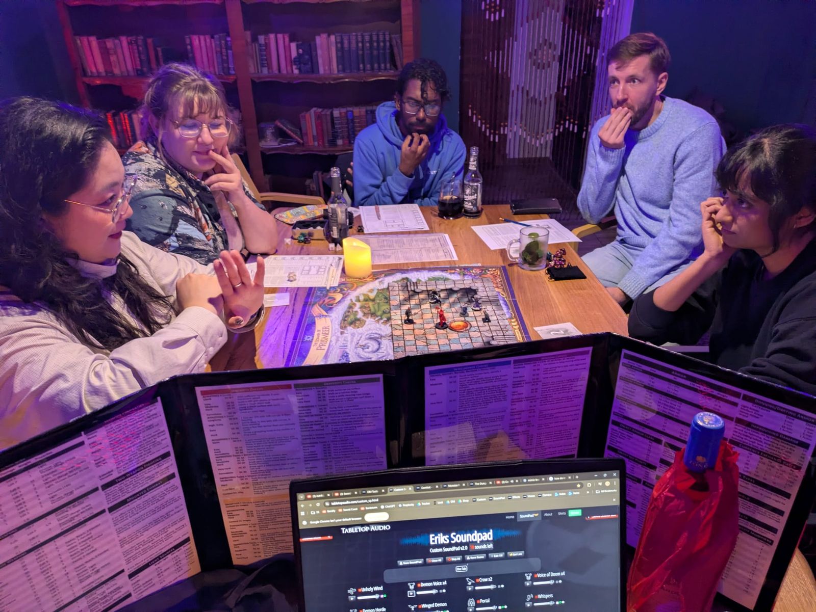 A dungeon battle map and miniatures under purple light, players thinking hard behind their character sheets.