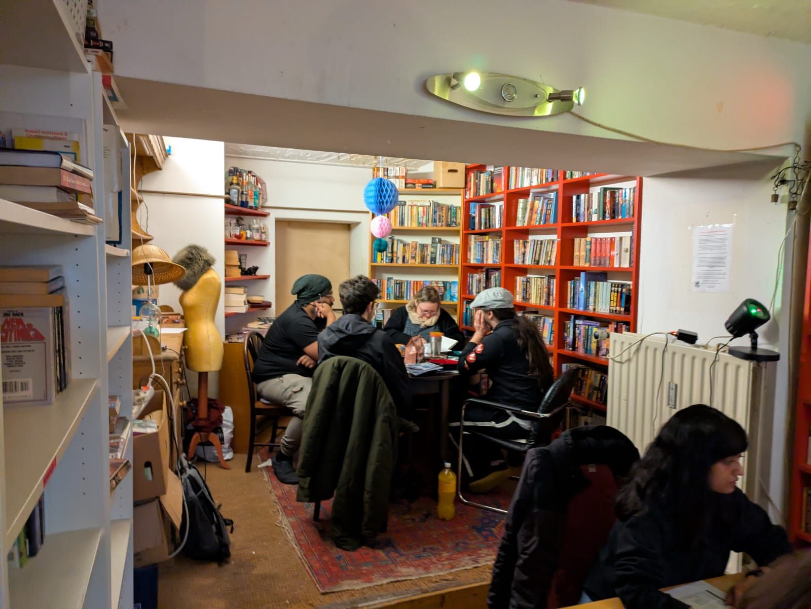 Two tables running at the same time in adjoining rooms of a bookshop, seen through a doorway.